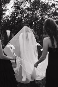 Bridesmaids holding veil as she walks away.