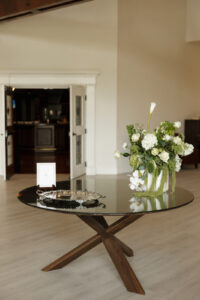 Welcome table detail shot at The Oaks at Plum Creek. Beautiful floral pieces with greenery and lilies.