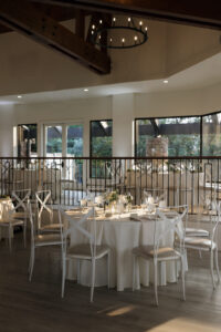 Detail shot of a tablescape at The Oaks at Plum Creek at sunset. Table features clean white and green decor with votives of candles and flowers.