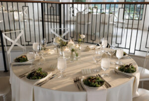 Detail shot of a tablescape at The Oaks at Plum Creek at sunset. Table features clean white and green decor with votives of candles and flowers.