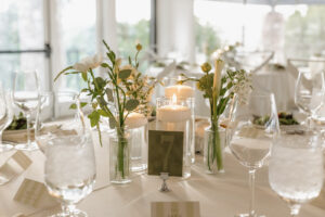 Detail shot of a tablescape of votives with white and green flowers. Modern, clean wedding aesthetic.