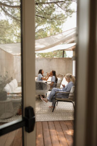 Bridesmaids doing each others makeup outside on the patio at the oaks at plum creek.