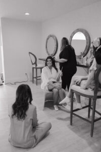 bride getting her hair done while drinking a mimosa.