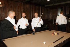 Groomsmen getting ready together by a pool table.