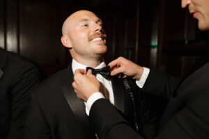 Groomsmen adjusting the grooms bowtie.